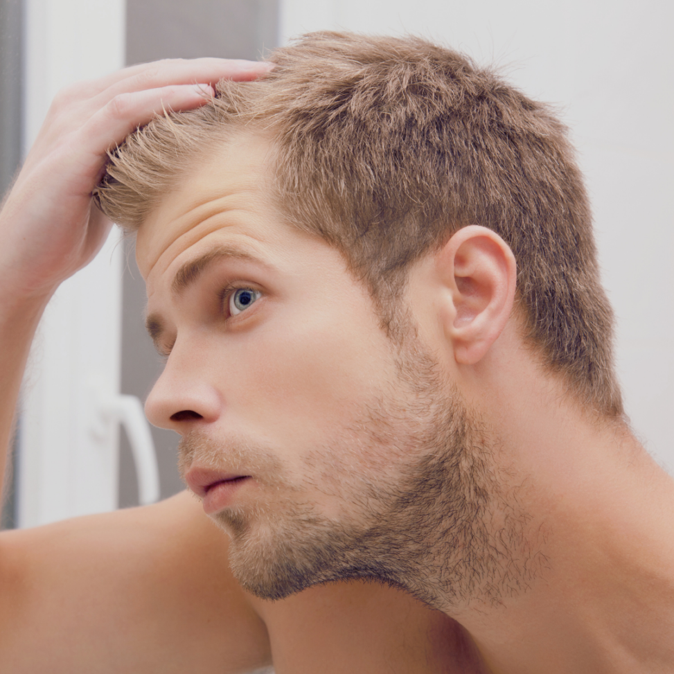 man with blonde hair looking at himself while touching his hair