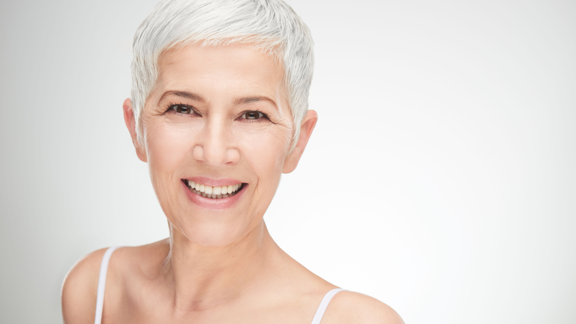 older white women with white hair smiling after her liquid facelift procedure