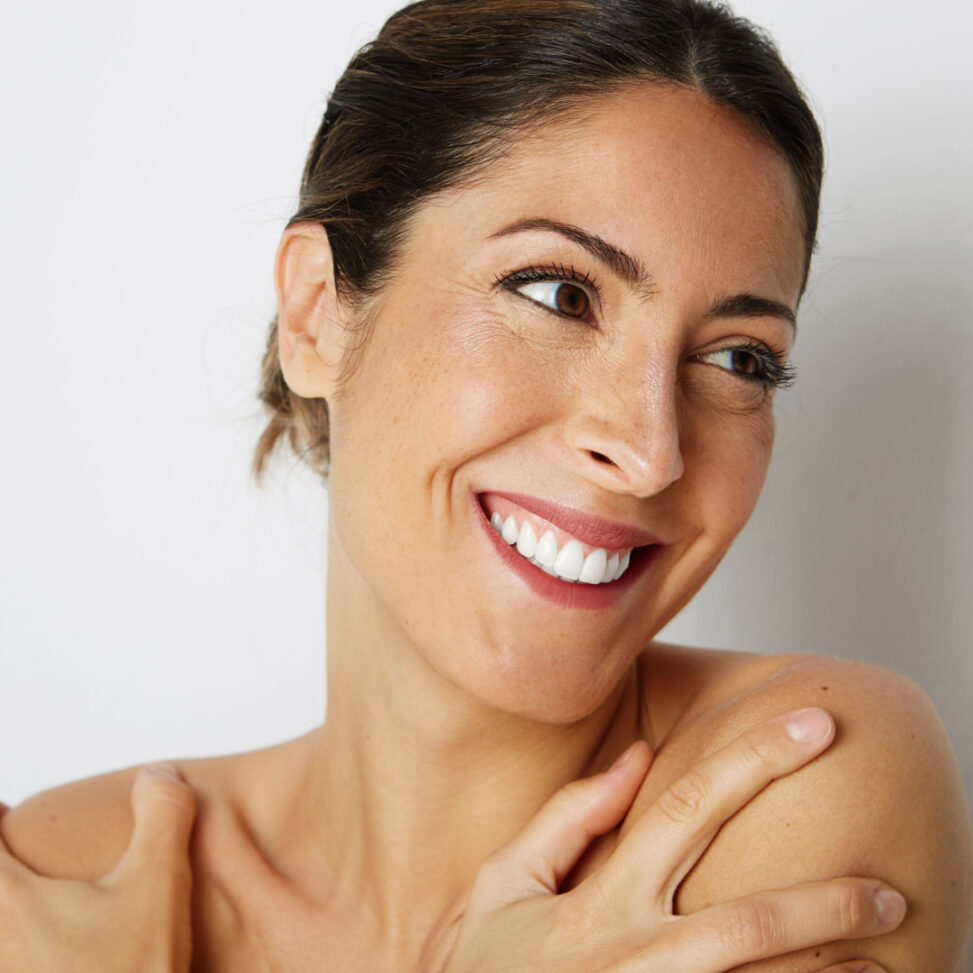 women smiling to the right side of the camera with her arms on her shoulders