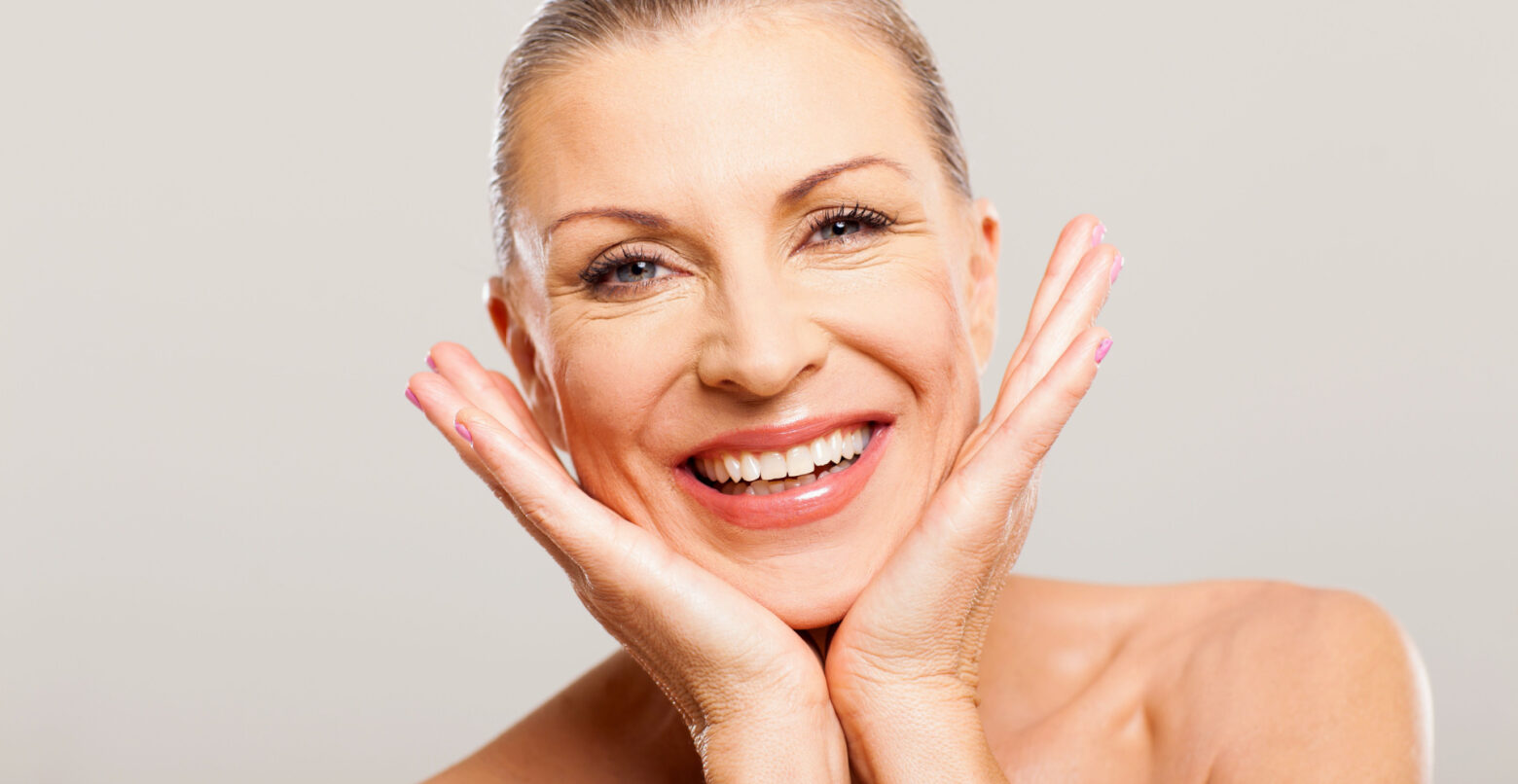 white older women looking at the camera with her hands on her face with a white background