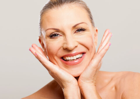 white older women looking at the camera with her hands on her face with a white background