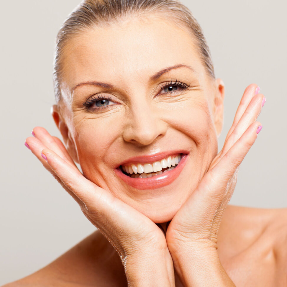 white older women looking at the camera with her hands on her face with a white background