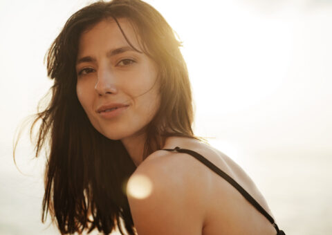 young beautiful women looking at camera while outside with the sun behind her head