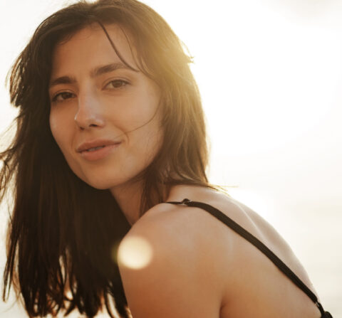 young beautiful women looking at camera while outside with the sun behind her head