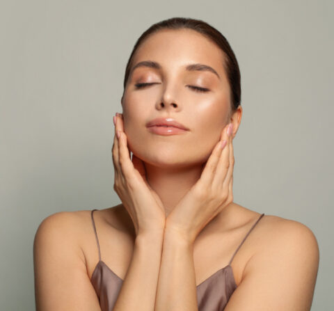 women touching her cheeks with a tan background