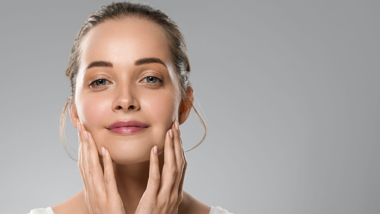 Woman with smooth, lifted skin gently touching her face after a PDO thread lift treatment, showcasing natural facial rejuvenation and firmness.