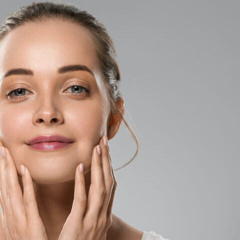 Woman with smooth, lifted skin gently touching her face after a PDO thread lift treatment, showcasing natural facial rejuvenation and firmness.