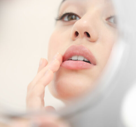 white women looking into mirror and touching her lips