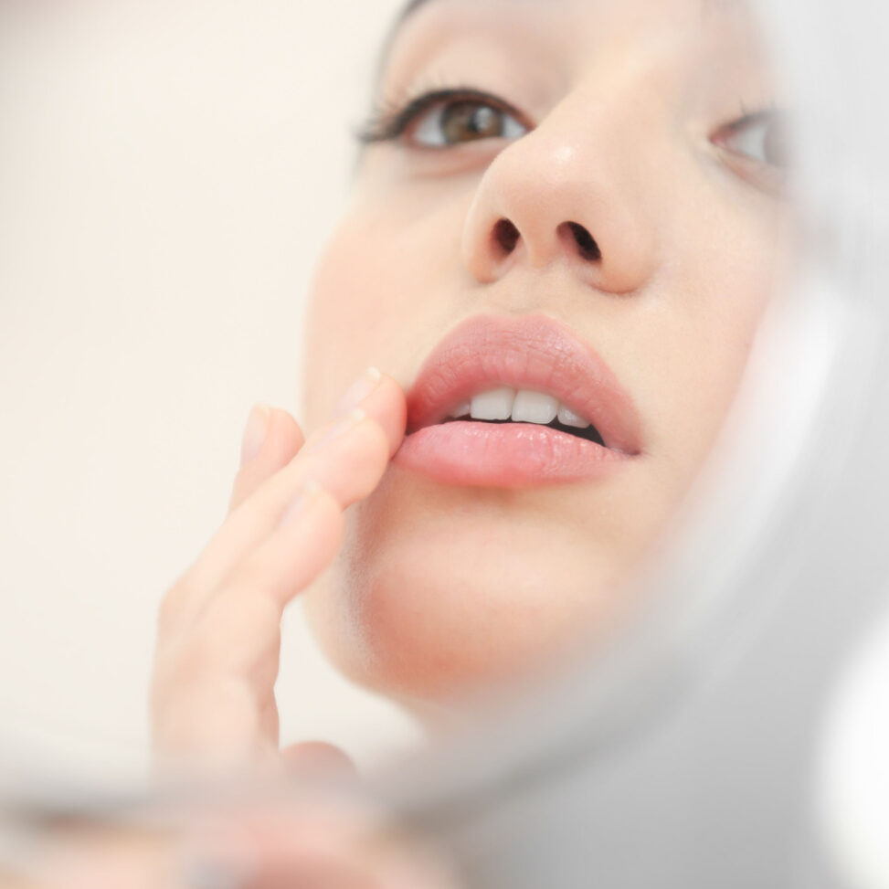 white women looking into mirror and touching her lips