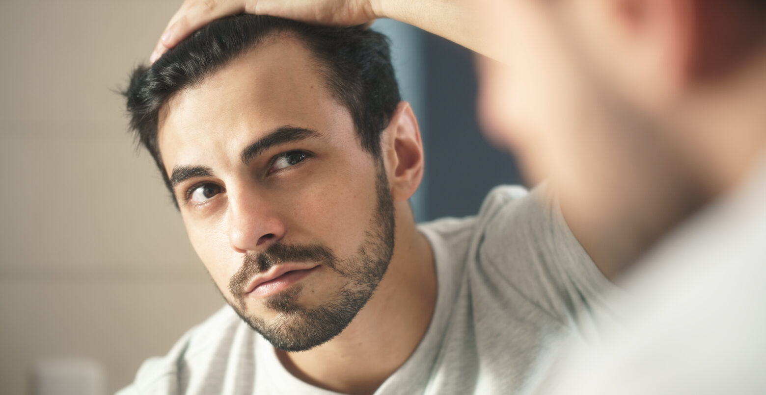 men with dark hair looking in mirror