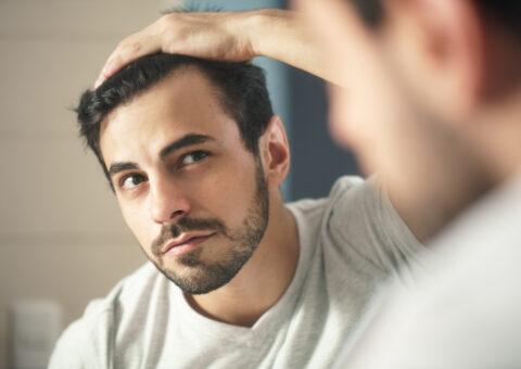 men with dark hair looking in mirror