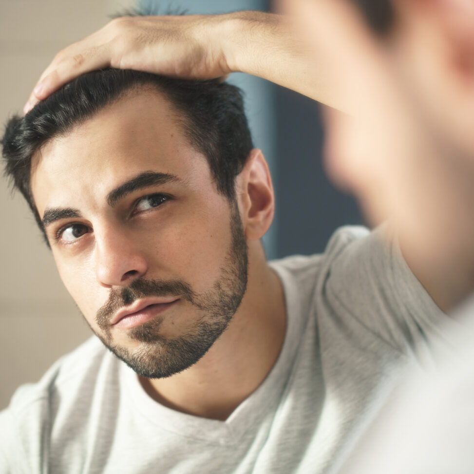 men with dark hair looking in mirror