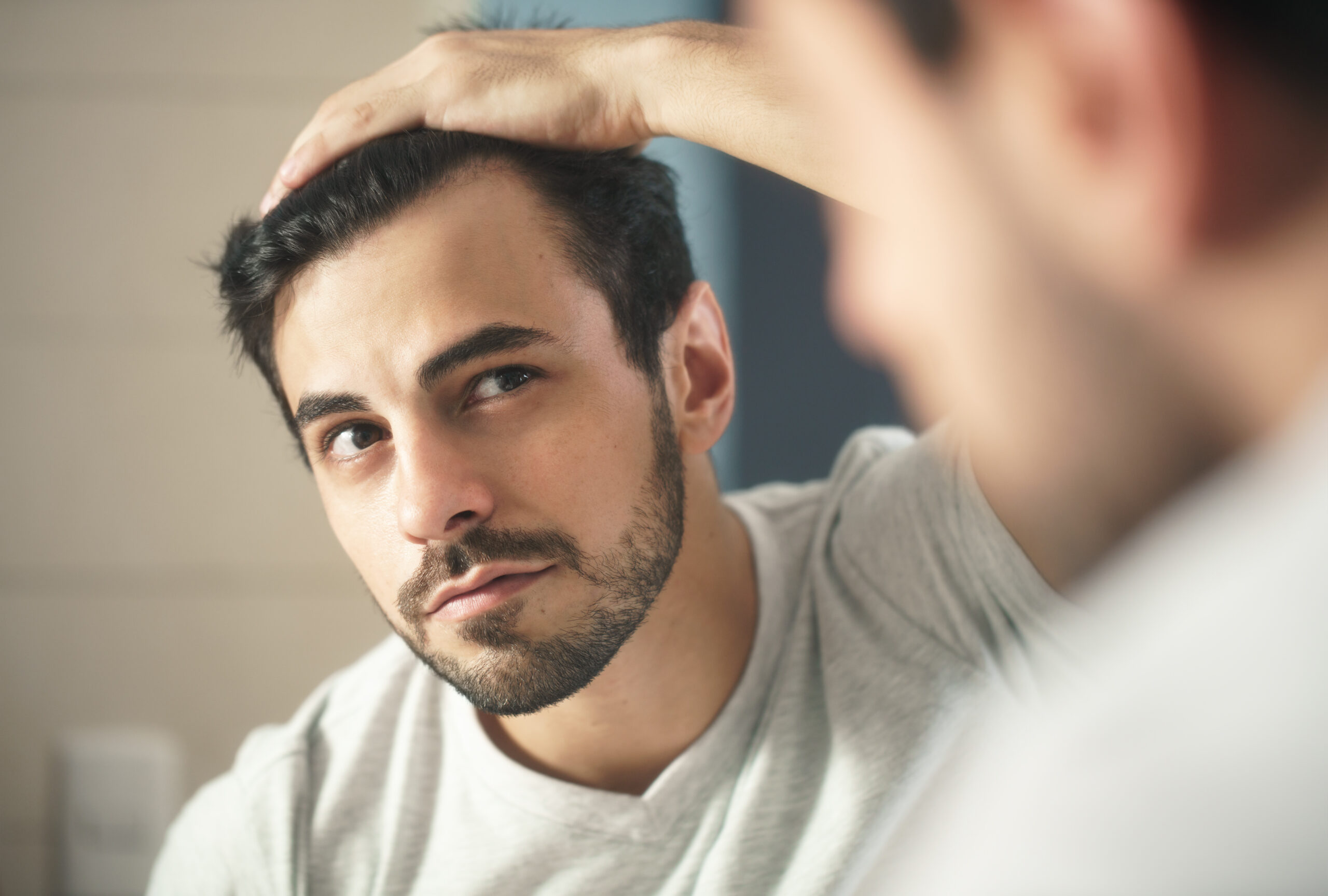 men with dark hair looking in mirror