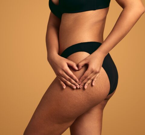 african american women toucher her thigh while wearing black underwear and bra with a tan background