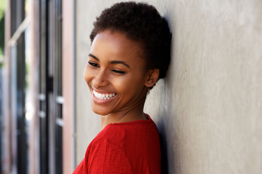beautiful black woman with red sweater looking down and smiling