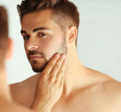 man looking at his chin in the mirror