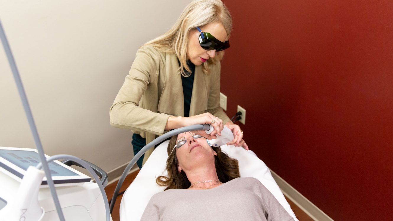 "Female patient receiving a BBL treatment from a clinician wearing protective eyewear in a medical aesthetics clinic."