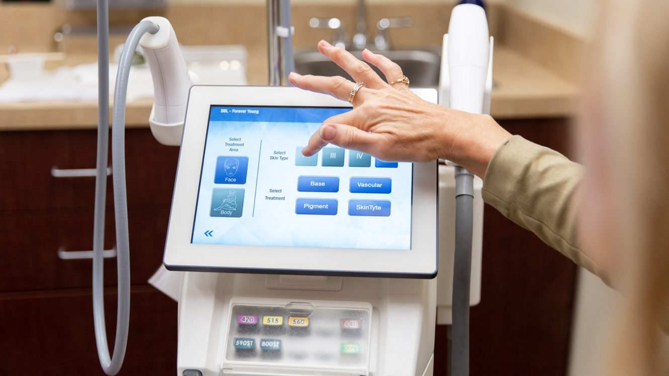 Technician selecting settings on a BroadBand Light (BBL) laser treatment device touchscreen at Skin Rejuvenation Clinic.