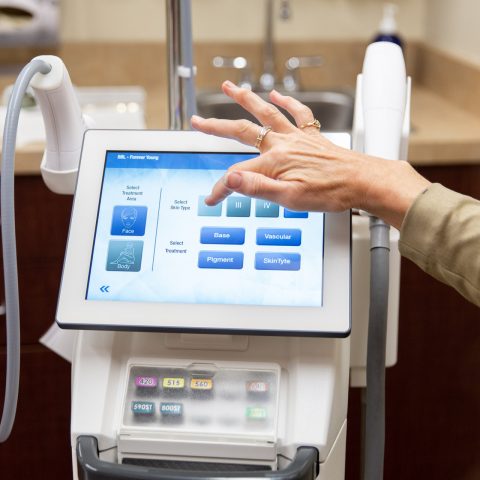 Technician selecting settings on a BroadBand Light (BBL) laser treatment device touchscreen at Skin Rejuvenation Clinic.