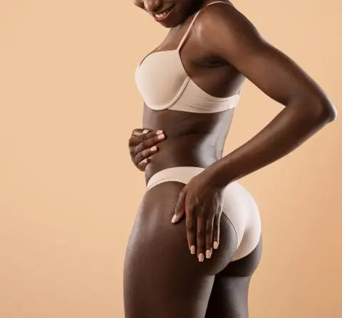 african american women touching her buttocks with a tan background