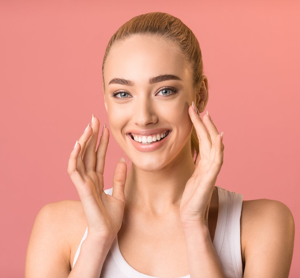 Cheerful Girl Touching Face Smiling To Camera, Pink Studio Background