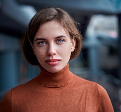 women looking at the camera with a straight face and orange shirt