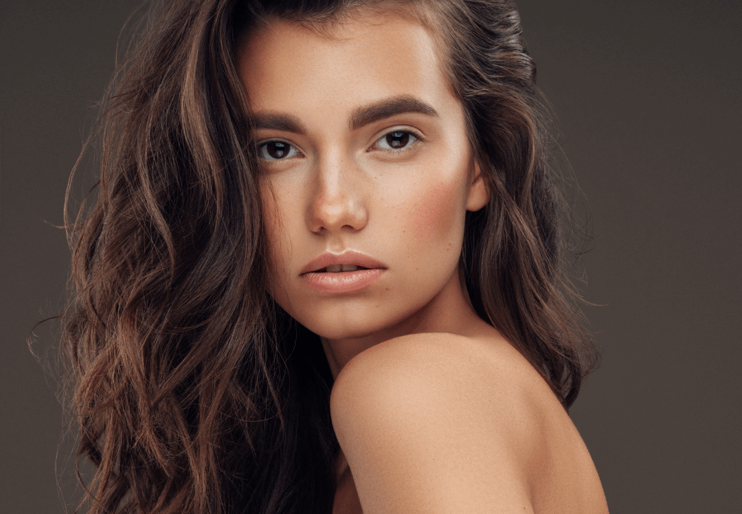 Woman with smooth, radiant skin and long wavy hair, showcasing the bright, even-toned complexion often achieved with BBL photofacial treatment.