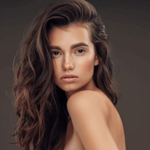 Woman with smooth, radiant skin and long wavy hair, showcasing the bright, even-toned complexion often achieved with BBL photofacial treatment.