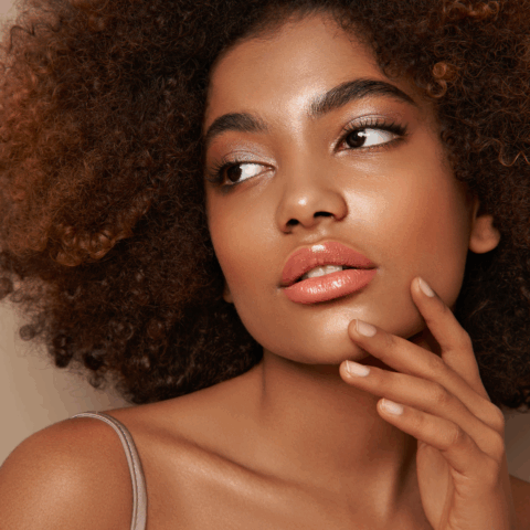 Woman with glowing, lifted skin touching her face, showcasing smooth, youthful results often associated with Ultherapy treatment.