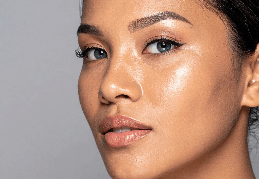 Close-up portrait of woman with smooth, glowing skin and natural makeup against gray background