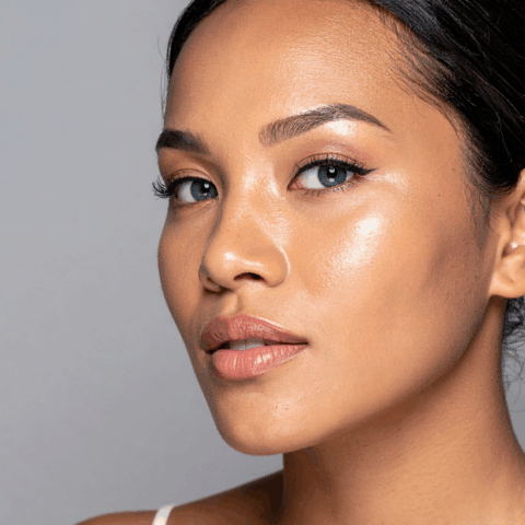 Close-up portrait of woman with smooth, glowing skin and natural makeup against gray background